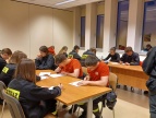 dzieci ubrane w mundury strażackie siedzą przy stołach i rozwiązuja test