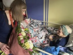 kobieta w okularach składa na ręce starszej kobiety bukiet kwiatów