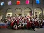 Zespół Pieśni i Tańca Dobczyce na Sardynii 2024, cały zespół w strojach ludowych przed budynkiem z arkadami