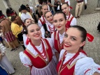 Zespół Pieśni i Tańca Dobczyce na Sardynii 2024, uśmiechnięte twarze, postacie kobiet w biało czerwonych strojach,  